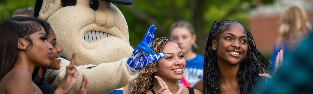 Students pose and smile with Louie the Laker
